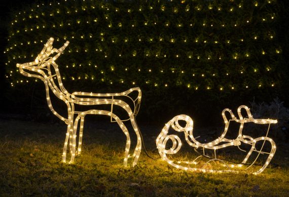 Reindeer with slay Christmas decoration on garden grass